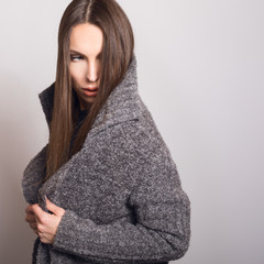 Beautiful young girl in gray coat posing in studio.