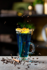 Burning blue cocktail garnished with orange and cinnamon
