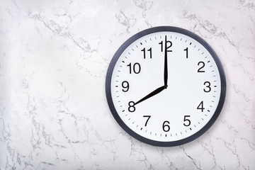Wall clock show eight o'clock on white marble texture. Office clock show 8pm or 8am on marble...
