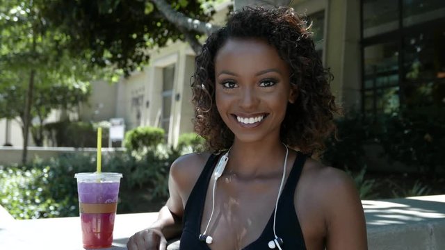 Pretty woman with a lemonade looks up and smiles at camera