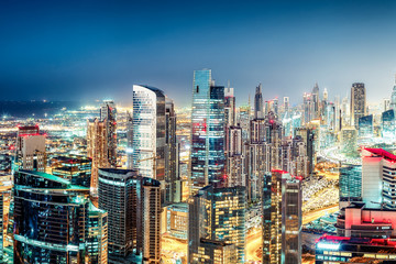 Fototapeta na wymiar Colourful nightime skyline of a big modern city. Dubai, United Arab Emirates. Aerial view on highways and skyscrapers.