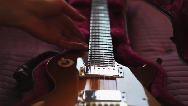 Man pulling out a guitar out of case. Closeup