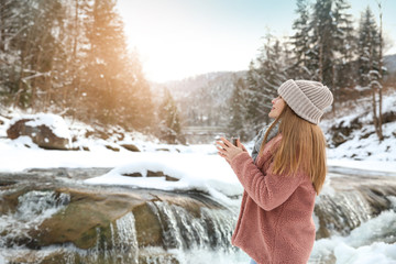 Beautiful woman with cup of hot mulled wine at snowy resort