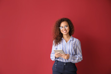 Young businesswoman with tablet PC on color background