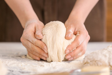 Female baker making dough in kitchen, closeup