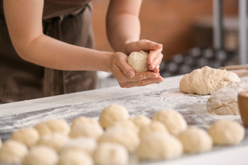 Female baker cooking buns in kitchen