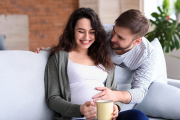 Happy pregnant couple resting at home