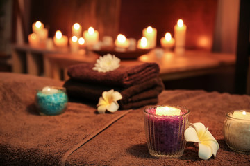 Burning candles and flowers on table in spa salon