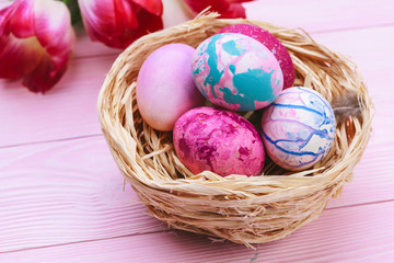Beautiful Easter composition with decorated eggs and flowers on pastel wooden background