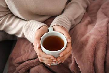 Young woman drinking hot tea at home, closeup