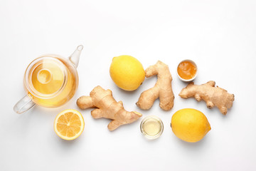 Teapot with healthy drink, lemon and ginger on white background