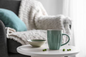 Cup of hot tea and candies on table in room