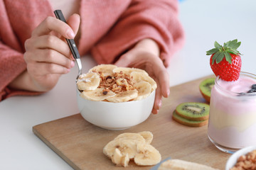 Young woman eating tasty yogurt at home, closeup