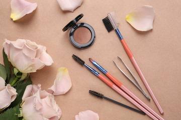 Obraz na płótnie Canvas Set of tools for eyebrows correction and flowers on color background