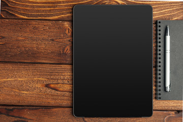 Tablet with notepad on wooden background
