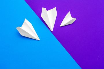white paper airplane on a color block blue and purple background