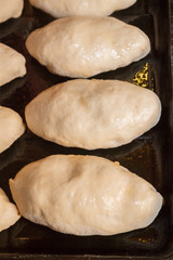 Freshly made pies lie on a baking sheet before cooking