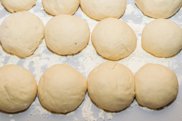 Fototapeta na wymiar Raw dough rolled into balls is on the table rolled in flour