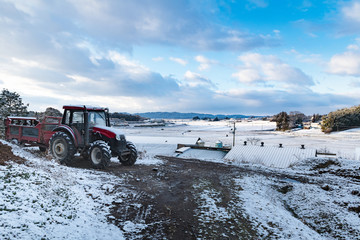 雪をかぶり出番を待つトラクターと堆肥散布機マニアスプレッダ