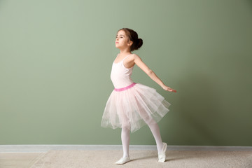 Naklejka premium Cute little ballerina dancing near color wall