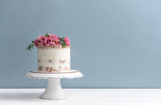 Sweet cake with floral decor on table against color background