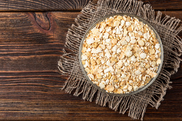 Dried pea flakes on dark wooden background.