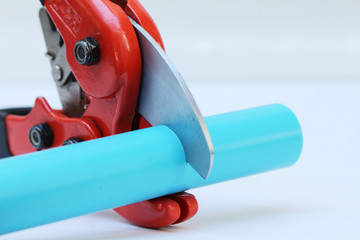 PVC water pipe cutter with red metal body, black rubber handle and sharp thick blade on white...