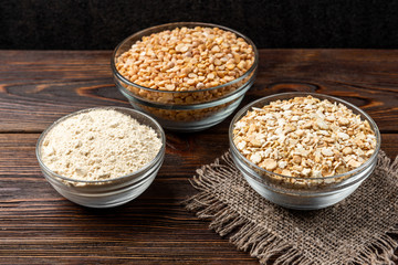 Dried pea, flakes and flour on dark wooden background.