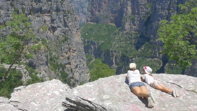mom and little girl are resting on the edge of the cliff, admiring the scenery of the beautiful canyon
