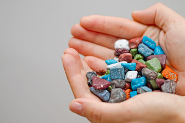 candy pebble in his hands, colored candy to eat