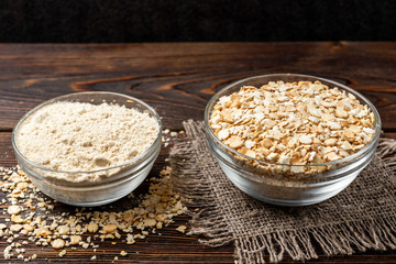 Dried pea flakes and flour on dark wooden background.