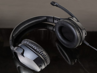 Naklejka na ściany i meble Black wired headset with full size headphones on dark surface