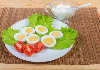 Halves of boiled chicken eggs, lettuce, tomatoes and mayonnaise sauce