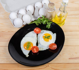 Fried eggs sunny side up, tomatoes on dish and ingredients