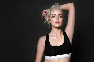 Fototapeta na wymiar Beautiful sexy blonde posing on a dark background in sports underwear