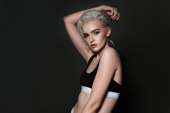 Beautiful sexy blonde posing on a dark background in sports underwear