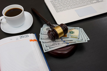 Judge gavel with dollar banknotes, laptop and coffee