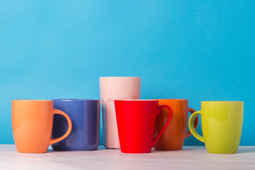 Many multicolored cups of coffee or tea on a blue background. The concept of a friendly company, a large family, meeting friends for a cup of tea or coffee