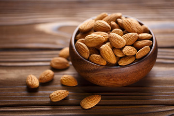 Close-up of delicious almonds in a wooden bowl on a wooden table