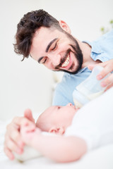 Obraz na płótnie Canvas Glücklicher Vater füttert sein Baby mit Milch