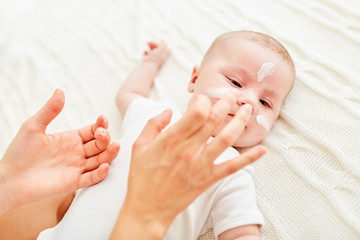 Mutter cremt Gesicht von Baby ein