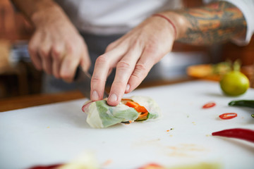 Closeup of professional chef cooking in restaurant kitchen making vegetable rolls, copy space