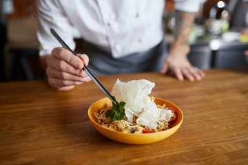 Close up of professional chef plating Asian cuisine dish in restaurant, copy space