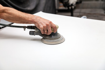 Preparation for painting a car element using sander and putty by a service technician leveling out...