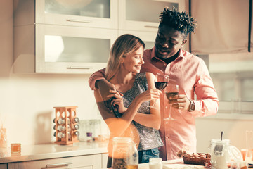 Beautiful couple clanging glasses while celebrating in the kitchen