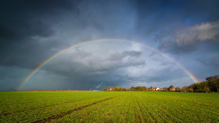 Regenbogen während Sturm Eberhard in Deutschland über einem Feld