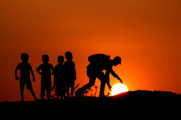 Silhouette of man with the kids touching Sun, Maharashtra, India.