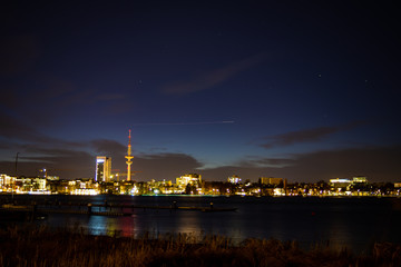 Fototapeta na wymiar A airplane's lights approaching Hamburg airport form a streak above downtown Hamburg at night