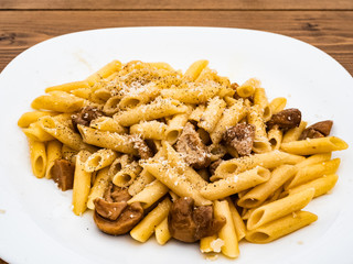 Italian cuisine, tasty short pasta dish with porcini mushrooms cheese and black pepper on wooden table outdoors for true epicureans