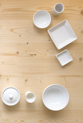 modern, white crockery, in different designs, stands on a light wooden background